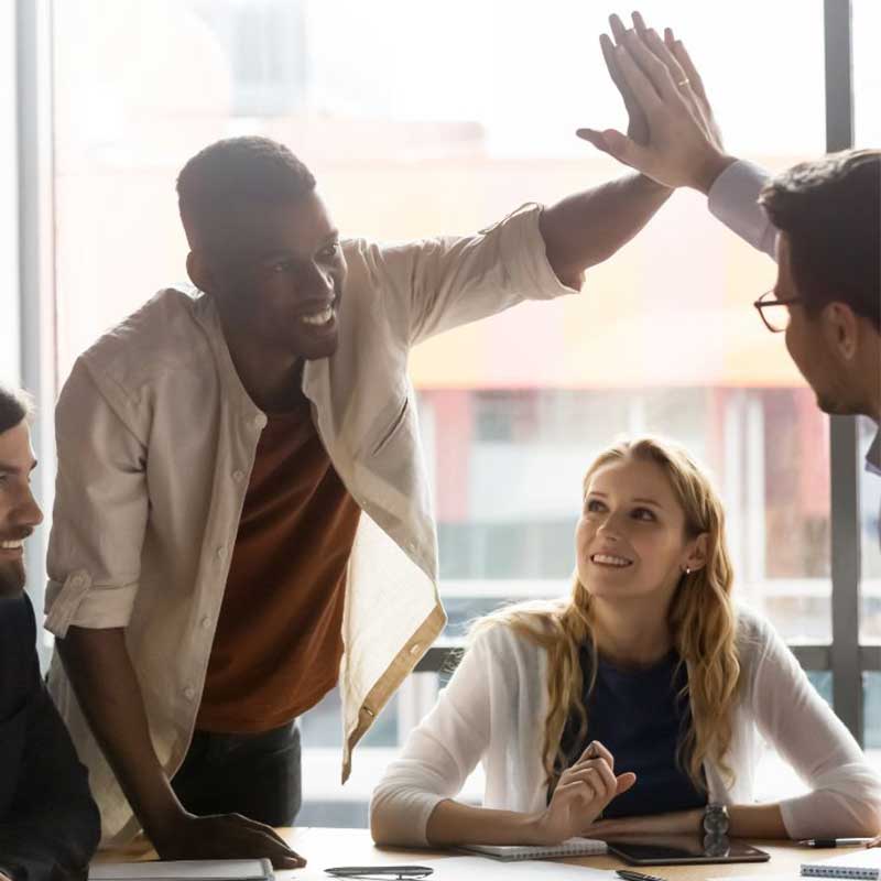 Colleagues celebrating with a high-five in a sunlit office