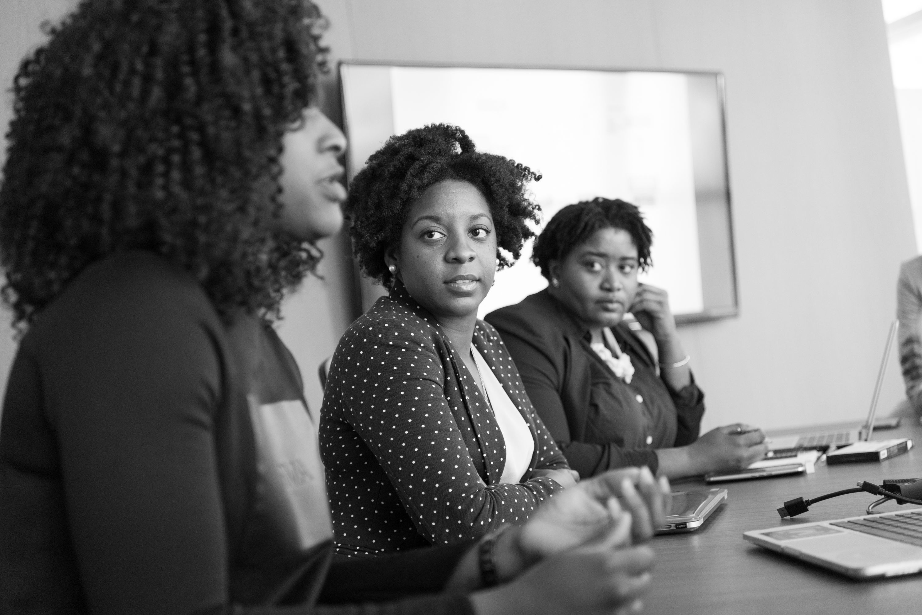 Three Black women sharing ideas during a professional leadership discussion